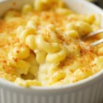 A bowl of creamy and golden Tini's Mac and Cheese Recipe garnished with fresh herbs.